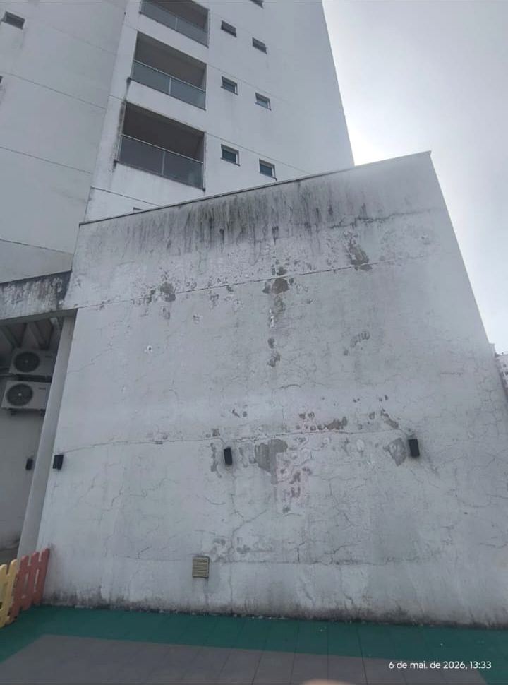 Empena de edifício com revestimento manchado, fissuras mapeadas e pontos de destacamento.